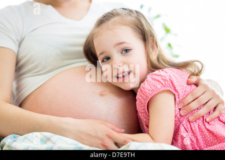 glückliches Kind Mädchen umarmt Bauch der schwangeren Mutter Stockfoto