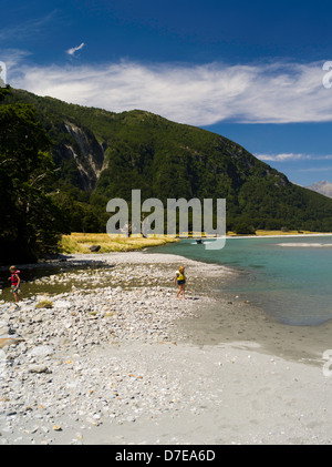 Ein Junge und ein Mädchen spielen des Flusses Wilkins mit einem Jetboat im Hintergrund Mount Aspiring National Park, Neuseeland Stockfoto