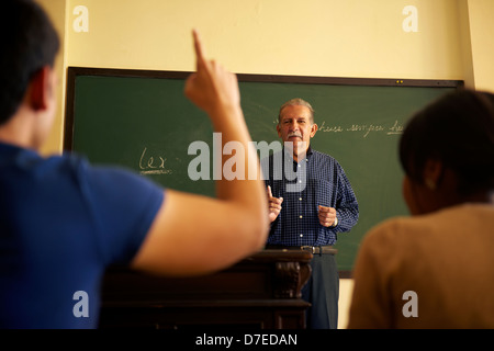 Studenten in College-Klasse mit Mann, die Hand heben, Frage, Lehrer Stockfoto