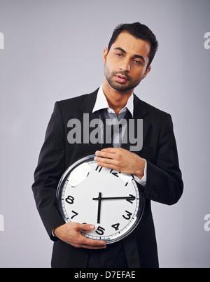 Verschlafene Büroangestellte hält eine Uhr Stockfoto