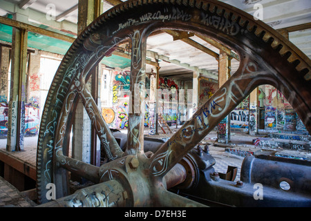 Industriekultur in das Innere des ehemaligen Eisfabrik Berlin mit einem eine sehr große Zahnrad und eine Menge von Graffiti, Deutschland Stockfoto