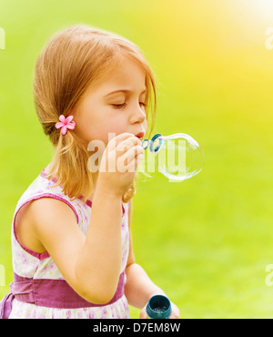 Closeup Portrait von niedlichen Babymädchen bläst Seifenblasen im Frühlingspark, Spaß im Freien, glückliche Kindheit Konzept Stockfoto