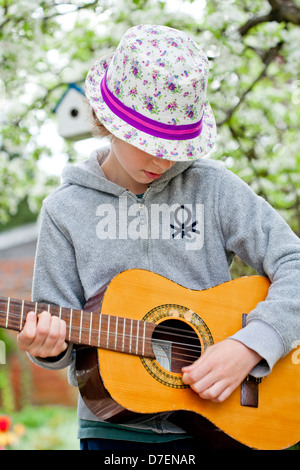 Porträt eines jungen spielen eine akustische Gitarre im Freien im Garten. Stockfoto