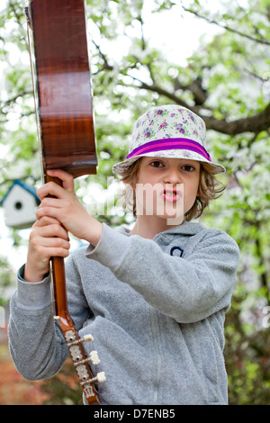 Porträt eines jungen spielen eine akustische Gitarre im Freien im Garten. Stockfoto