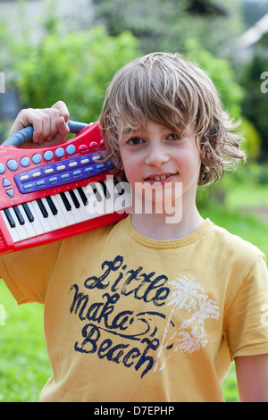 Bildnis eines Knaben mit Tastatur spielen im Freien im Garten. Stockfoto