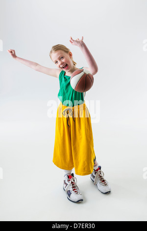 Ein junges Mädchen in übergroßen Basketball Trikot Shorts und Schuhe einen Basketball wirft; Anchorage Alaska USA Stockfoto