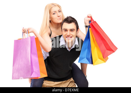 Ein junger Mann geben eine Huckepack Fahrt zu einer Frau mit Einkaufstüten isoliert auf weißem Hintergrund Stockfoto