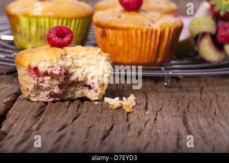 Einige ganze Muffins auf einem Kuchengitter Kuchen und einem gebissen Muffin in der front Stockfoto