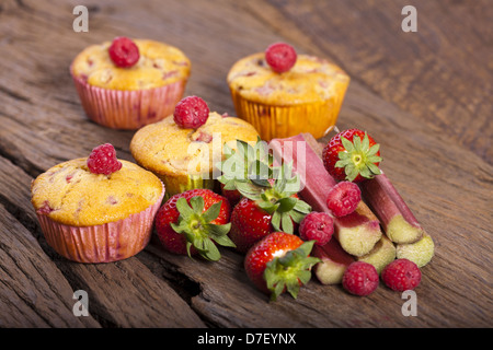 Einige ganze Frucht Muffins und frischen und köstlichen Früchten Zutaten auf einem alten Holzbrett Stockfoto