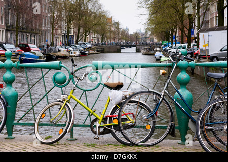 Bunte Fahrrad gegen einen bunten Geländer, auf einer Brücke über einen Kanal in Amsterdam.Transport Fahrräder, Autos, Boote. Stockfoto