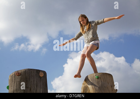 Mädchen, balancieren auf Baumstamm versucht, einen großen Schritt Stockfoto