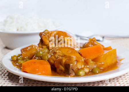 engere Schuss von Huhn-Eintopf mit Kartoffeln, Möhren, grüne Erbsen in Tomatensauce und Schüssel mit Reis Stockfoto