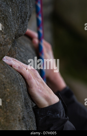 Die Kalkhaltigen weiblichen Kletterer Hände auf gritstone Rock Stockfoto