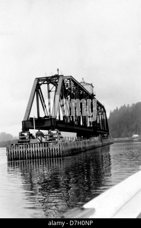 Dieses historische Foto zeigt die Eisenbahnbrücke über den Umpqua River in Reedsport, Oregon. Die Brücke ist Teil des Southern Pacific Railroad-Systems, was die Verkehrsinfrastruktur der Region hervorhebt. Stockfoto