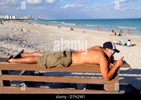 Miami Beach, Florida, South Pointe Park, Point, Atlantik, Wasser, Männer Männer Erwachsene Erwachsene, Sonnenbaden, Sonnenbaden, Liegen, Sand, öffentlicher Strand, Surfen, Checki Stockfoto