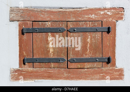 Das kleine Fenster, die durch eine rote Sonnenblenden in dem alten Haus - im freien Bild geschlossen. Sonnigen Tag Stockfoto