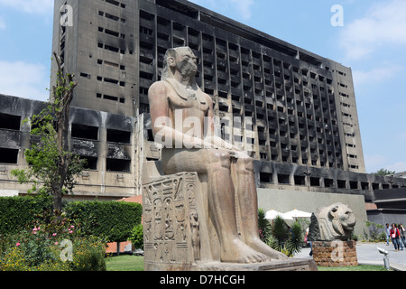 Ägypten, Kairo. Alten geformten Figuren am Hof des ägyptischen Museums, im Hintergrund ausgebrannten NDP-Partei-Gebäude Stockfoto