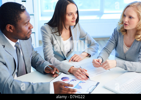 Zwei Mitarbeiter anhören des Geschäftspartners während der Arbeit mit Papieren der Tagung Stockfoto