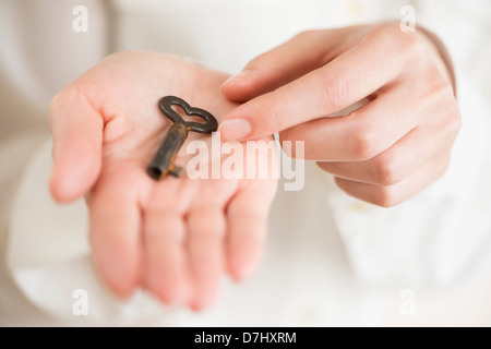 Weibliche Hand hält herzförmige Schlüssel Stockfoto