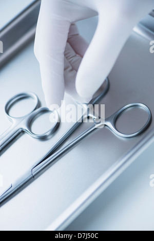 Nahaufnahme von Hand in OP-Handschuhen Wahl zahnärztliche Pinzette, Studio gedreht Stockfoto