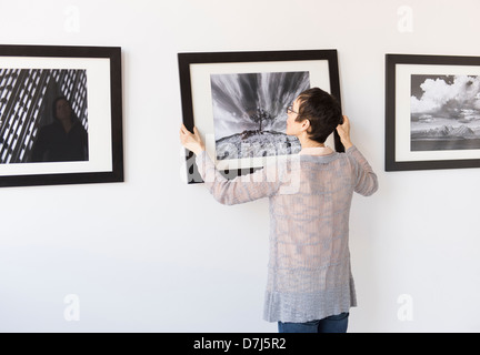 Frau hängen Fotografien in Kunstgalerie Stockfoto