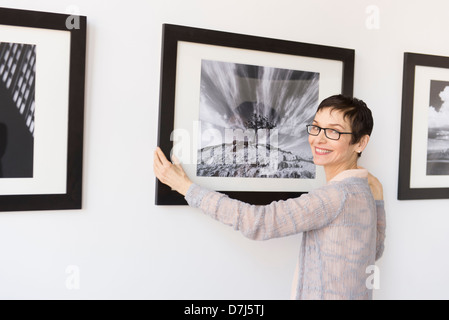 Frau hängen Fotografien in Kunstgalerie Stockfoto