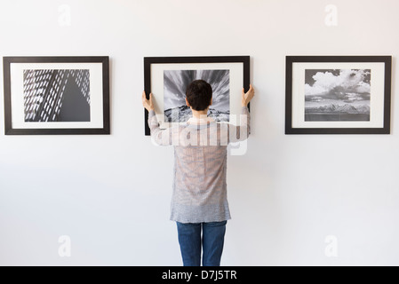 Frau hängen Fotografien in Kunstgalerie Stockfoto