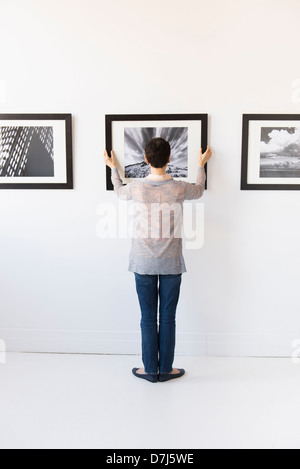 Frau hängen Fotografien in Kunstgalerie Stockfoto