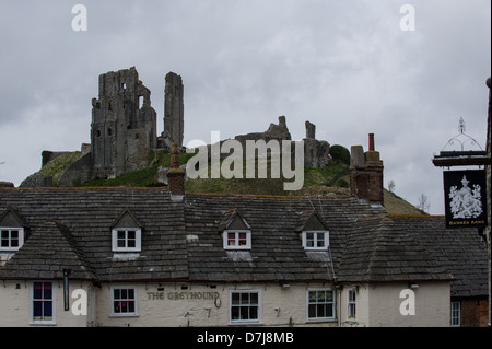 National Trust laufen Corfe Castle Ruinen von Corfe Dorf unter launisch grauen Himmel mit The Greyhound Pub im Vordergrund gesehen Stockfoto