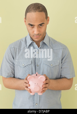 Junger Mann verwahrenden Piggy bank Stockfoto