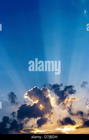 Sonnenstrahlen piercing durch blauen Himmel bei Sonnenuntergang Stockfoto