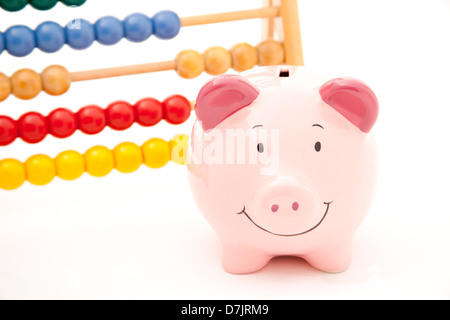 Lächelnd vor einem Abakus vor einem einfarbigen Hintergrund rosa Sparschwein steht. Stockfoto