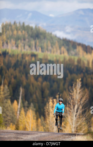 USA, Montana, Felchen, Frau Radfahren auf ländlichen Bergstraßen im Herbst Stockfoto