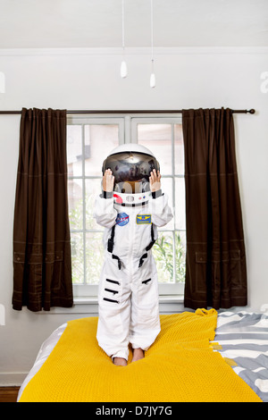 Porträt der junge Stand auf seinem Bett im Raumanzug Stockfoto