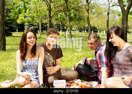 Nahaufnahme-Potrtrait von zwei Teenager Paare mit einem Picknick auf einem Teppich in bewaldete Landschaft nahe beieinander sitzen Stockfoto