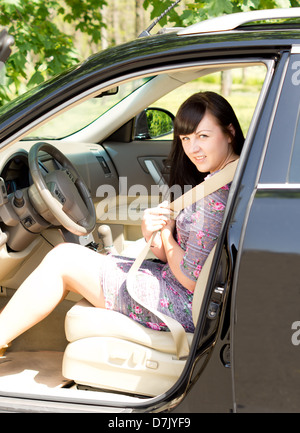 Junge attraktive Brünette auf ihren Sicherheitsgurt im Auto sitzen. Stockfoto