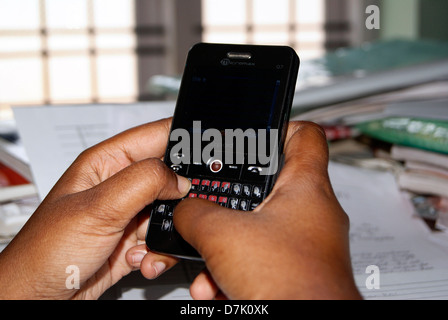 Junge College-Mädchen, die Eingabe von SMS auf ihrem Mobiltelefon auf dem Hintergrund der Studie Bücher in Kerala Indien Stockfoto