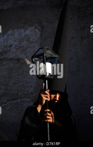 Ein Büßer gekleidet in schwarz hält eine Kerze während der Semana Santa in La Antigua Guatemala, 29. März 2013. Stockfoto