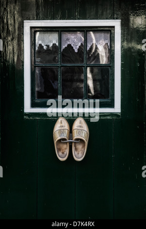 holländische Holzschuhe an einer grünen Tür mit einem Fenster hängen Stockfoto