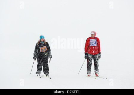 Zwei Skifahrer in die 35 km Freistil Kategorie nähern sich die Oberfläche der Mora-Vasaloppet in in der Nähe von Whiteout Bedingungen. Stockfoto