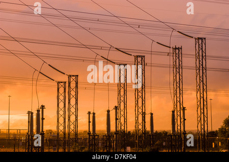 Power Transmission Türme mit orangefarbenem Sonnenuntergang Himmel. Stockfoto