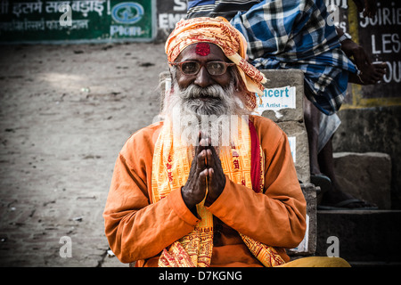 Ein Sadhu oder heiliger Mann sitzt und singt an den Ghats am Fluss Ganges in Varanasi oder Benares. Stockfoto