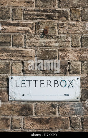 Ein Wegweiser in Richtung ein Briefkasten an einer Wand in Southwold, Suffolk UK Stockfoto