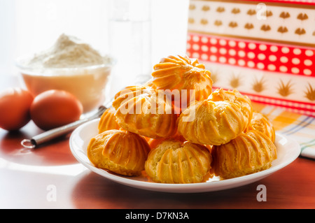 Puffs in einer Platte. Eiern, Mehl und Peitsche in in der Nähe der Fenster im Hintergrund Stockfoto