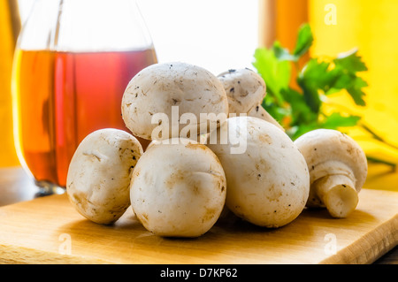 Ganze Champignons mit Essig und Petersilie. Ein Fenster mit Vorhang im Hintergrund Stockfoto