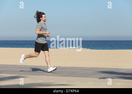 Mann am Meer auf den Strand mit dem Meer im Hintergrund läuft Stockfoto