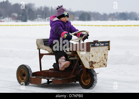 Youngster fährt eine alte Vintage Rasenmäher Messer See während einer Pre-Event-Parade vor den ersten jährlichen Rasenmäher Eis Rennen. Stockfoto