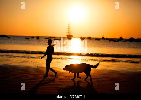 Frau Jogger geht ihr Hund am Strand bei Sonnenuntergang in San Juan del Sur, Nicaragua, 12. März 2013. Stockfoto