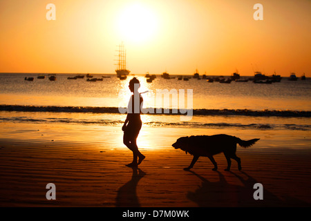 Frau Jogger geht ihr Hund am Strand bei Sonnenuntergang in San Juan del Sur, Nicaragua, 12. März 2013. Stockfoto