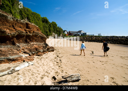 Junges Paar walking Hund am Strand, Jacksons Bay, Barry Island, Vale of Glamorgan, South Wales, UK. Stockfoto